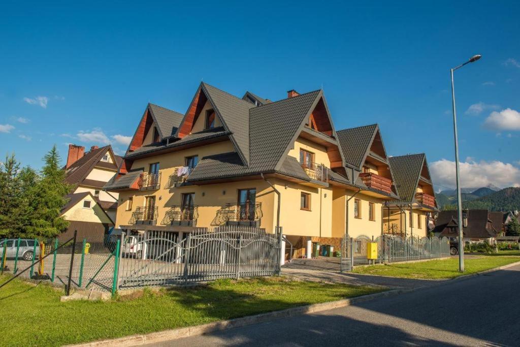 a large house with a gambrel roof on a street at Apartamenty i pokoje gościnne Nowita in Zakopane