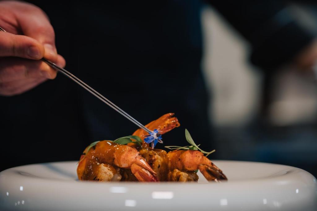 a person eating a piece of food on a plate at Porto Covo Praia Hotel & SPA in Porto Covo