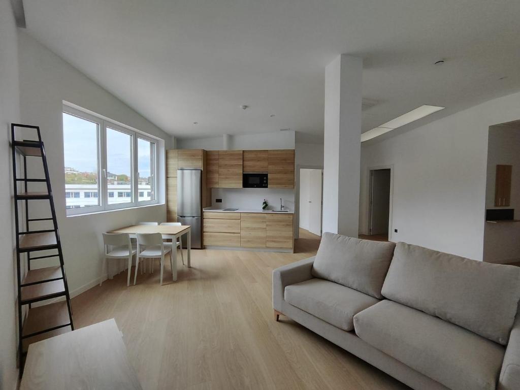 uma sala de estar com um sofá e uma cozinha em Apartamentos Pillotegi parking gratuito em San Sebastián