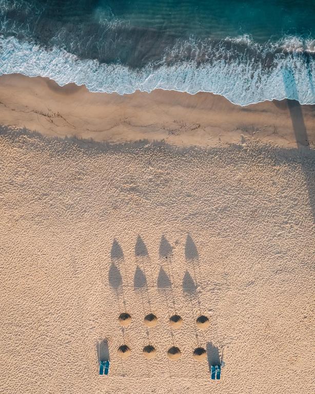 a group of seven umbrellas in the sand on a beach at Porto Covo Praia Hotel & SPA in Porto Covo