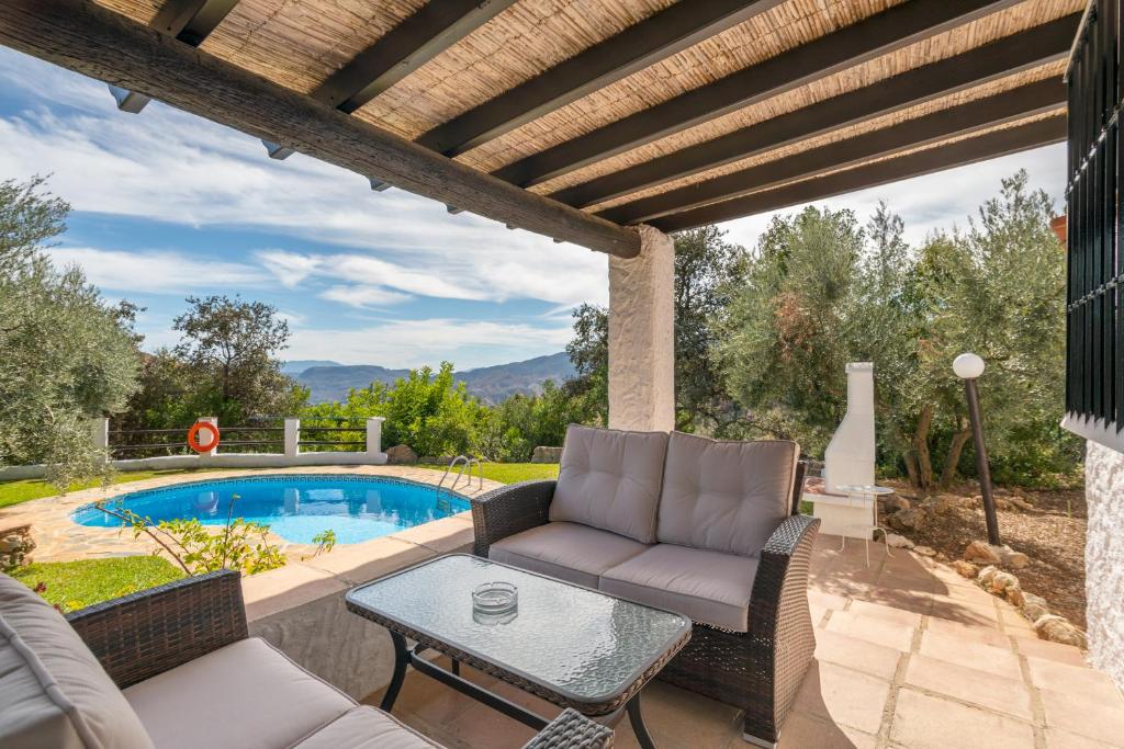 a patio with a couch and a table next to a pool at El Chorro Villas Casa Rosaleda in El Chorro