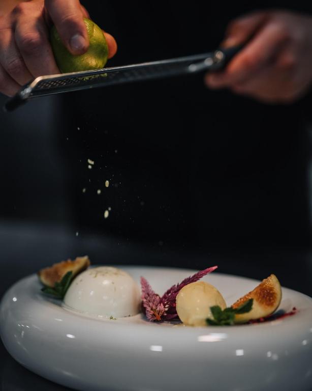 a person holding a pickle over a plate of food at Porto Covo Praia Hotel & SPA in Porto Covo