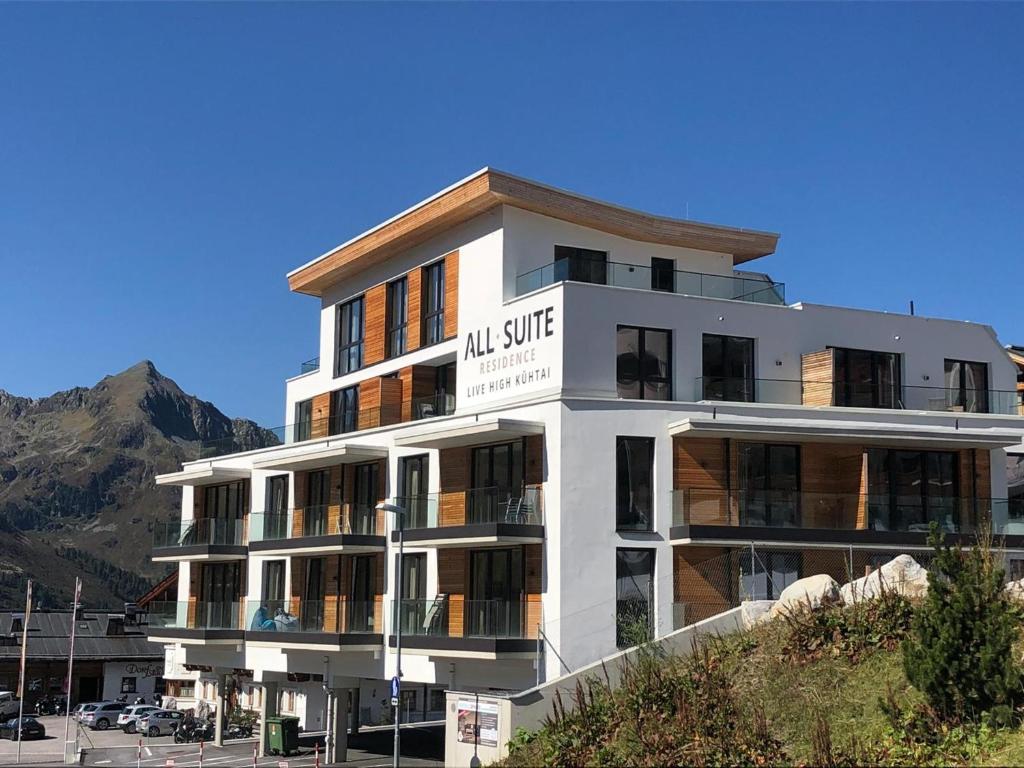 un grand bâtiment blanc avec une montagne en arrière-plan dans l'établissement All-Suite Resort Kühtai, à Kühtai