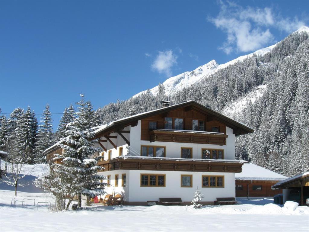 a large building in the snow with a mountain at Haus Lärchenhof in Holzgau