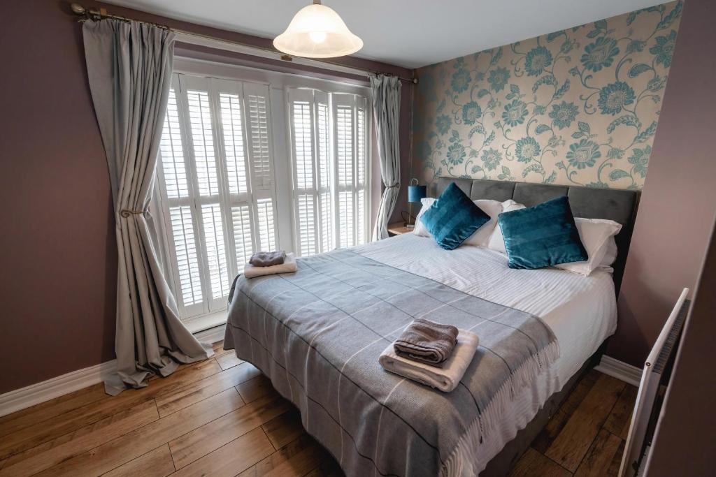 a bedroom with a bed with blue pillows and a window at Blue Anchor House in Maryport