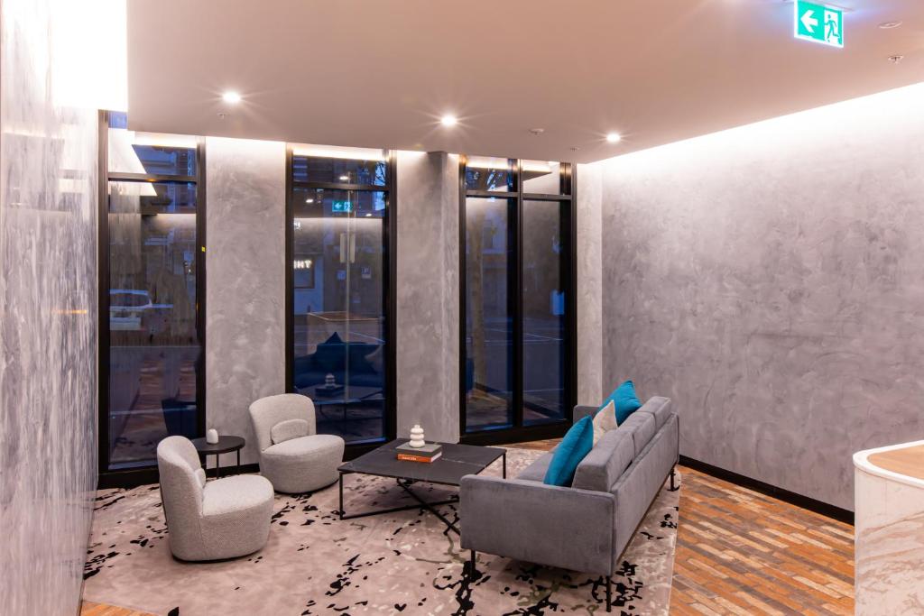 sala de estar con sofá, sillas y ventanas en The Marker Apartments Melbourne en Melbourne