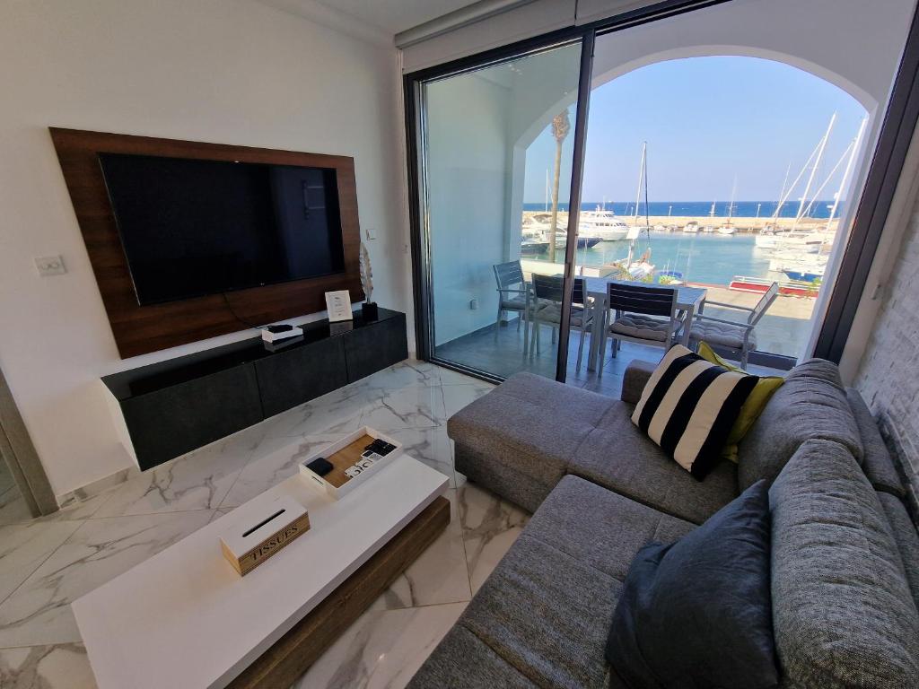 ein Wohnzimmer mit einem Sofa und einem Flachbild-TV in der Unterkunft The Belvedere Latchi Marina in Lachi