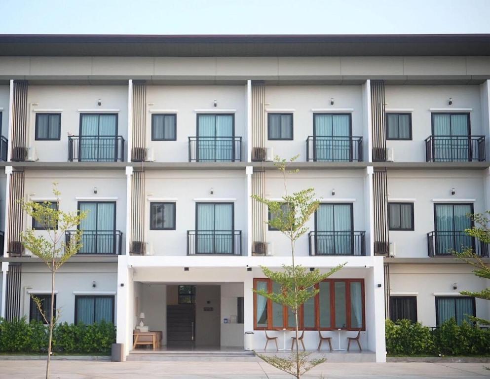 een groot wit gebouw met ramen en een binnenplaats bij Thezen Hotel in Yasothon