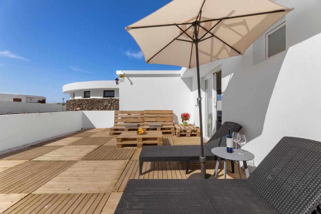 a balcony with a table and an umbrella at Famara Loft 12 in Famara