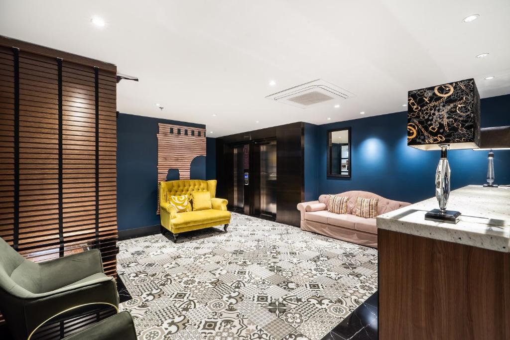 A richly styled lounge with blue walls, yellow and pink sofas, and patterned flooring.