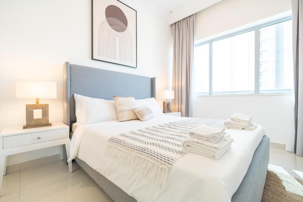 - une chambre blanche avec un lit et une fenêtre dans l'établissement Deluxe 21st Flr Huge 3BR Pool & Gym Near Mall, à Dubaï