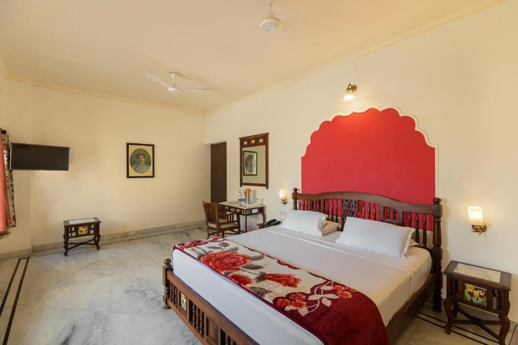 a bedroom with a large bed with a red headboard at WelcomHeritage Kalyan Bhawan Hotel in Jaisalmer