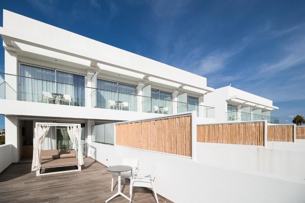 a white house with a balcony with a table and chairs at Petit Sagitario Adults only in Ciutadella