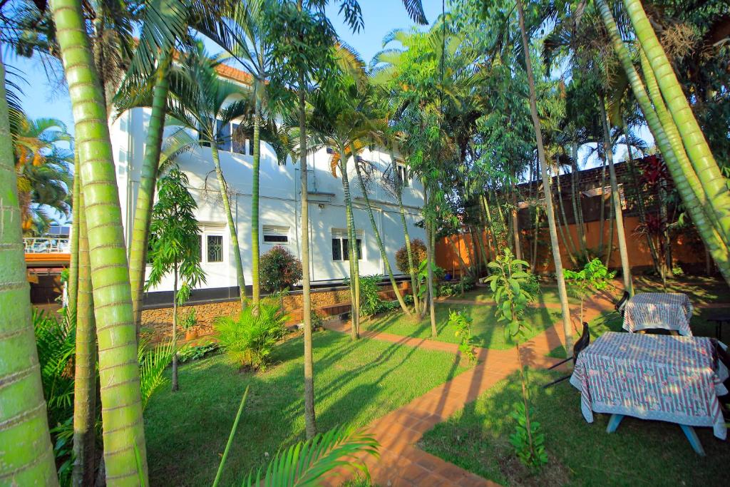 a garden with a table and chairs and palm trees at Ambassador Bridge Motel in Jinja