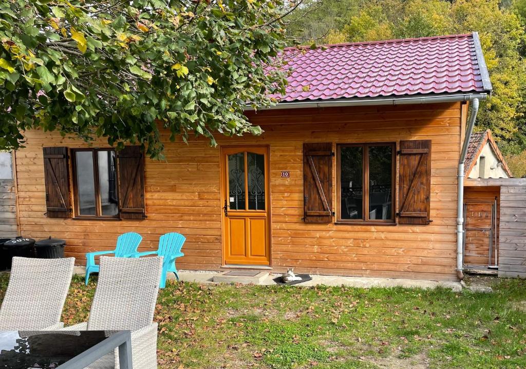 una pequeña casa con 2 sillas y una puerta naranja en Villa Guillaumette, en Châteauneuf-les-Bains
