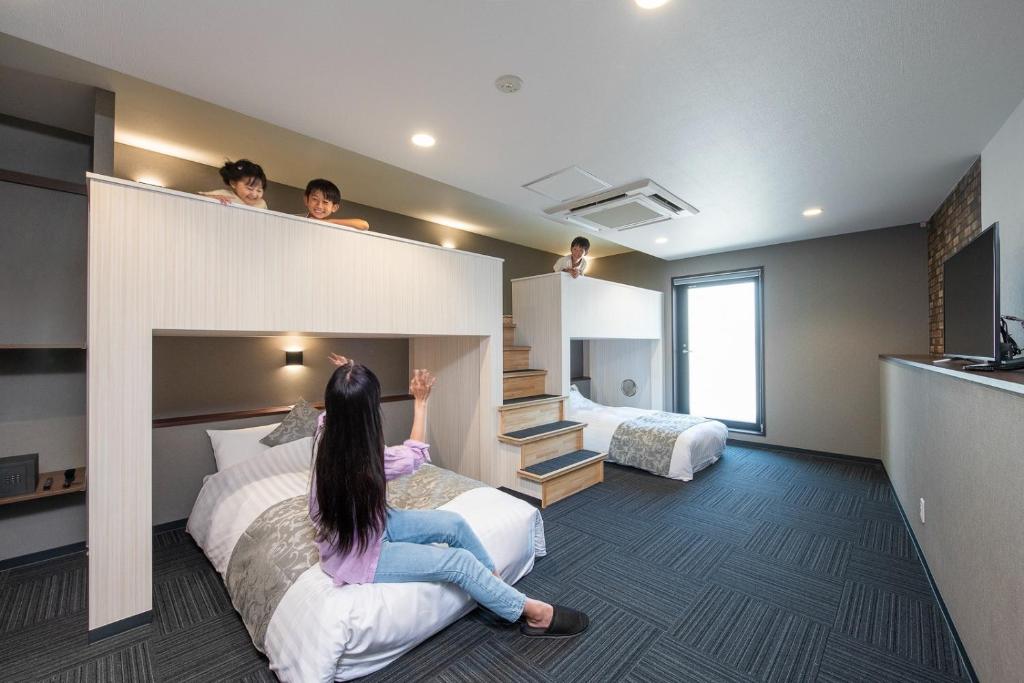 una donna seduta su un letto in una stanza d'albergo di ＥＮＴ ＴＥＲＲＡＣＥ ＡＳＡＫＵＳＡ - Vacation STAY 85544v a Tokyo