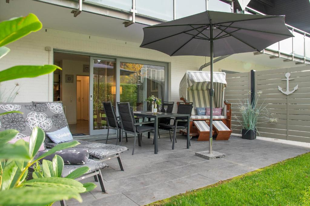 un patio con mesa, sillas y sombrilla en Badeweg 4 Haus Bullerbü, App 6, en Scharbeutz