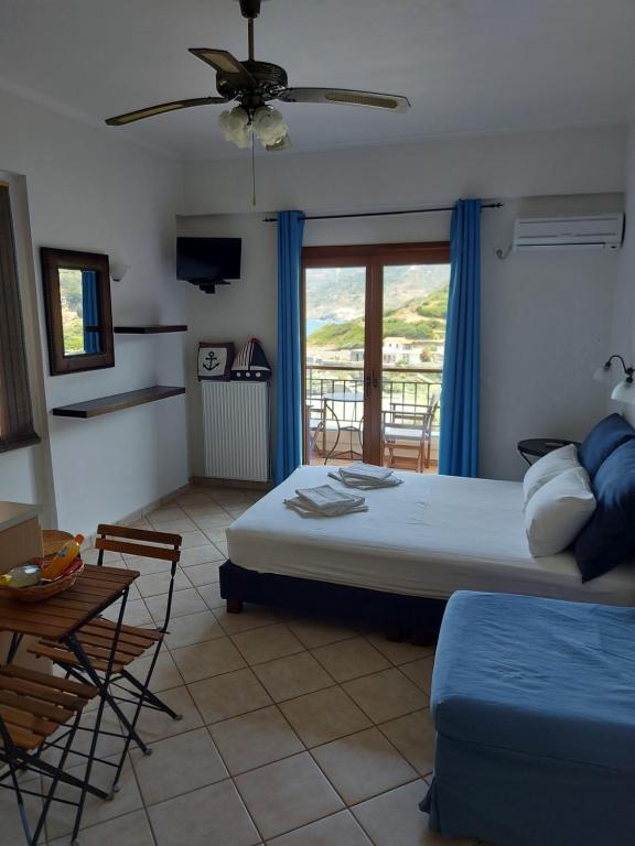 a bedroom with a bed and a table and a window at Anarrousa Studios & Apartments in Évdhilos