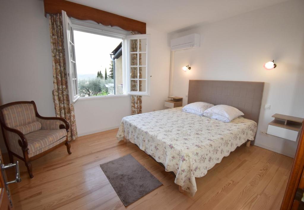 a bedroom with a bed and a window and a chair at Chambre d'hôtes et Spa en Luberon in Volx