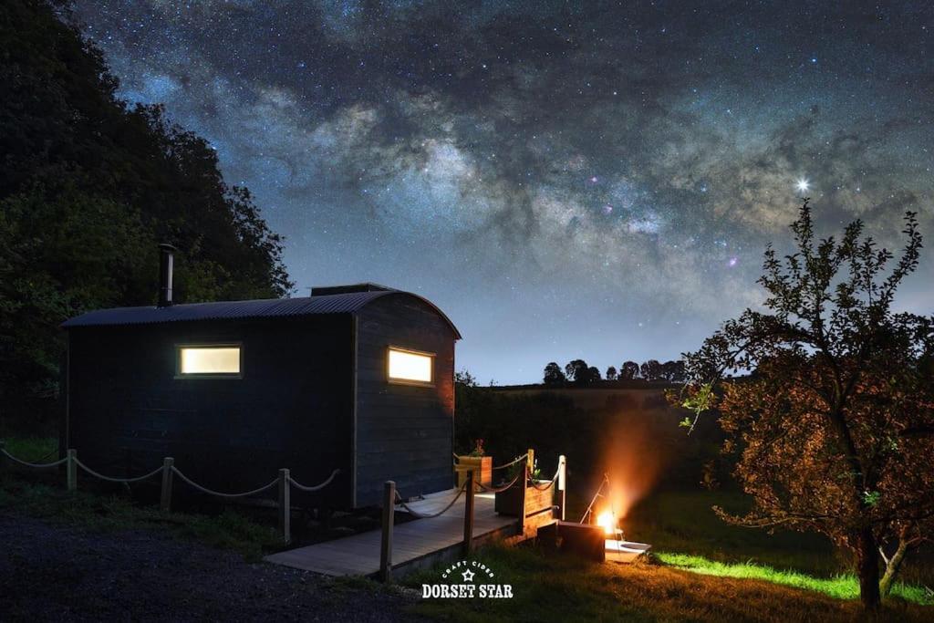 a cabin in a field at night with a fire at Orchard retreat off grid shepherds huts in Dorset in Dorchester