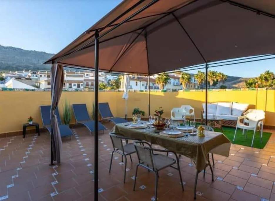 une terrasse avec une table, des chaises et un parasol dans l'établissement Apartamento con vistas a la Sierra de El Torcal, à Villanueva de la Concepción