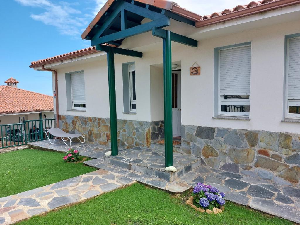 una casa con postes verdes en el patio delantero en El Gato Gordo - Riders Hostel, en Cudillero