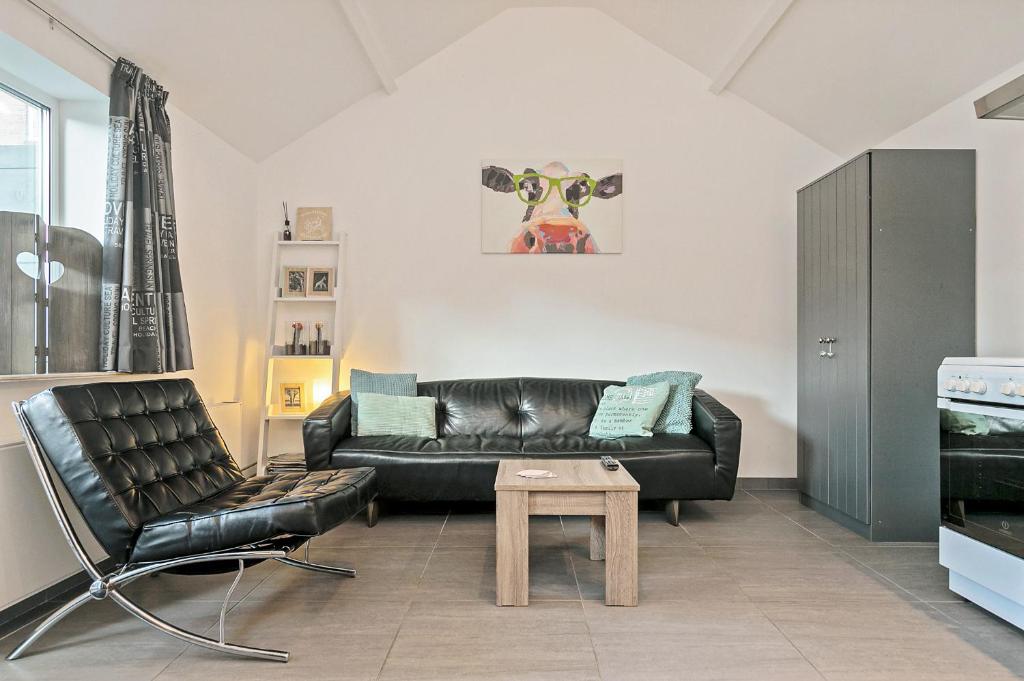 a living room with a black leather couch and a table at Hello Zeeland - Vakantiehuis Wijngaardstraat 12 in Domburg