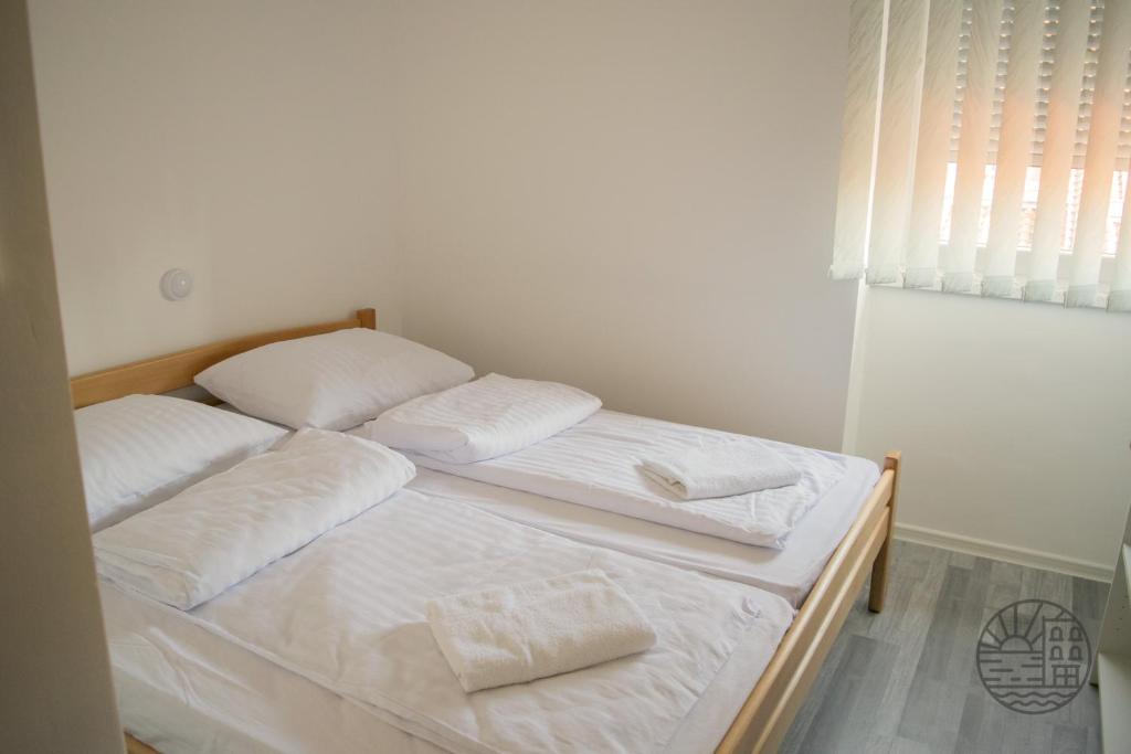 Duas camas num quarto com lençóis e almofadas brancos em Počitniški dom Portorož / Portoroz Holiday Home em Portorož
