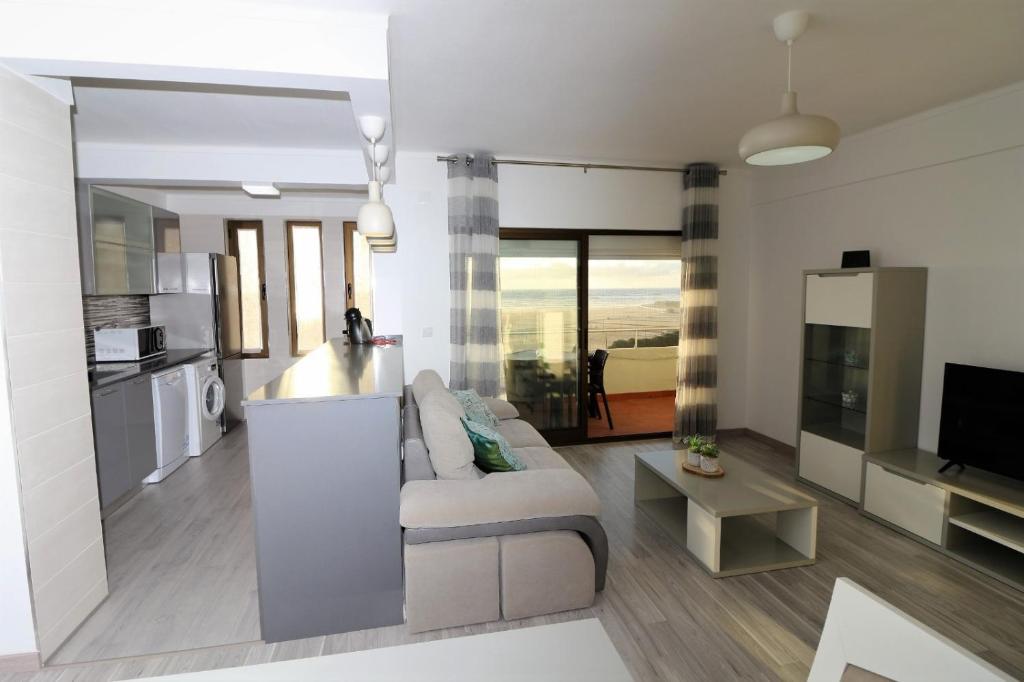 een woonkamer met een bank en een tv en een keuken bij Tonay Sol 7D in Buarcos