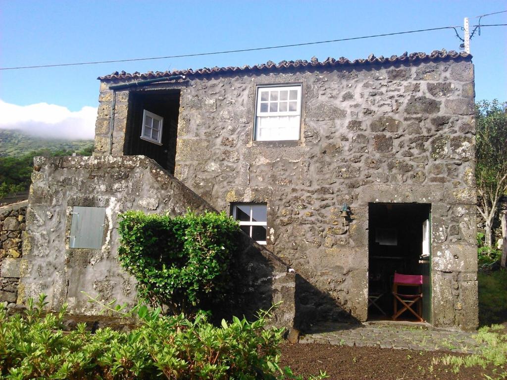 una antigua casa de piedra con una silla roja en la puerta en Holiday home in Praínha, Pico, Azores, en Prainha de Cima