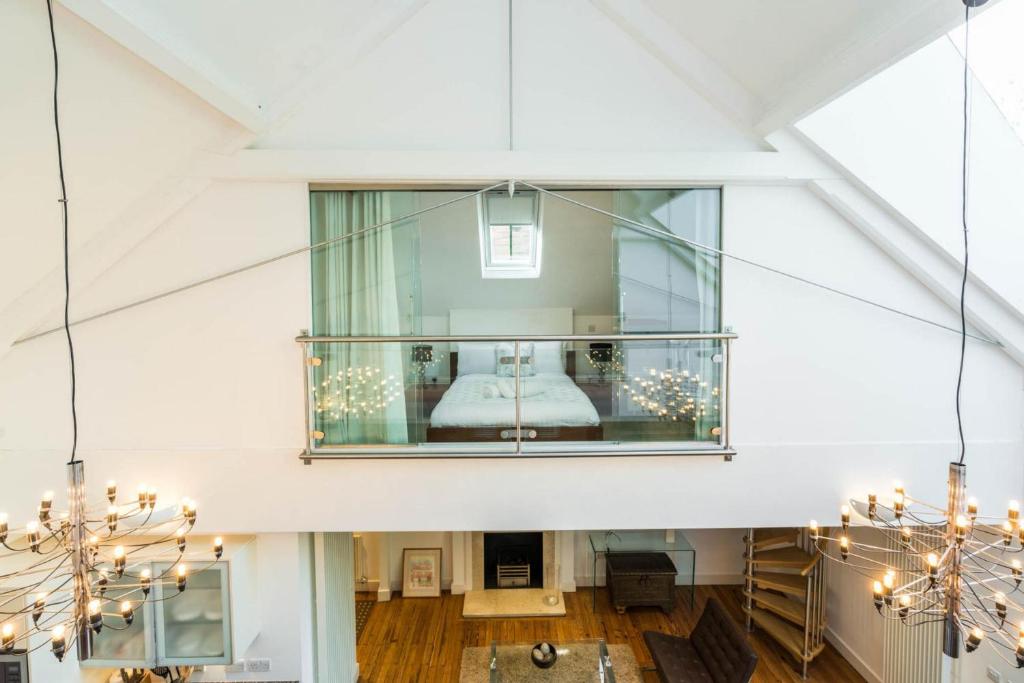 Cette grande chambre blanche dispose d'une fenêtre avec un lit. dans l'établissement Unique 2 Bedroom converted Artists Studio, à Londres