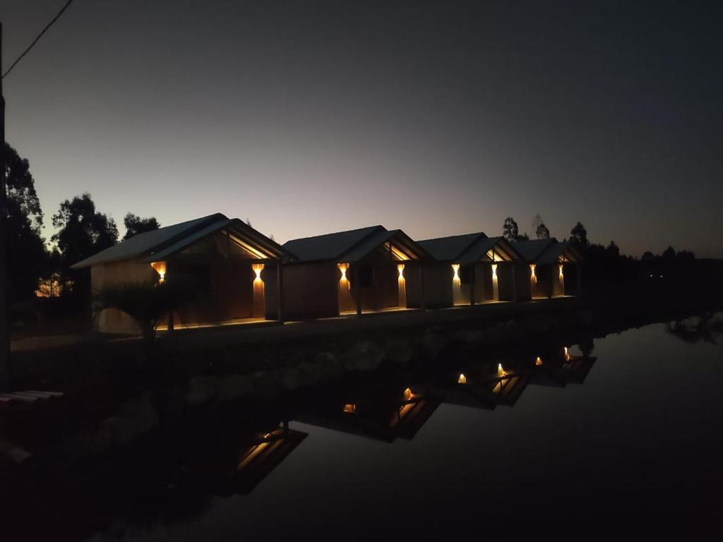 a row of lodges with lights on the water at night at Pousada Refúgio do Sol in Cambará