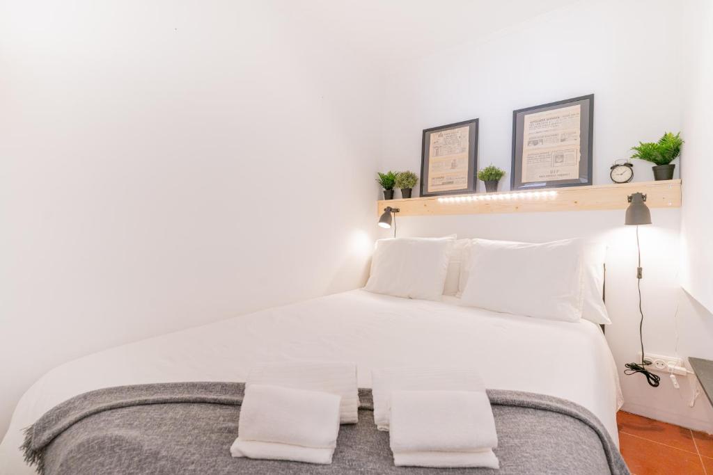 een slaapkamer met een wit bed en 2 witte kussens bij Alfama Nest in Lissabon