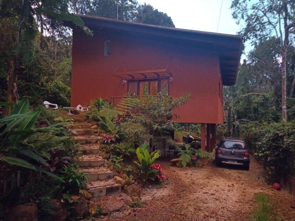 czerwony dom z samochodem zaparkowanym przed nim w obiekcie Casa da Praia do Félix w mieście Ubatuba