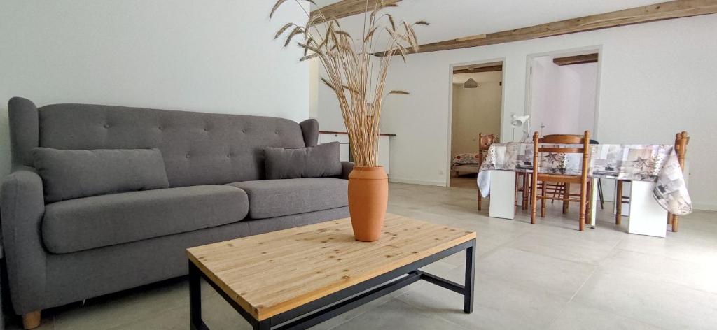 sala de estar con sofá y jarrón sobre una mesa en Le gîte de l'Ecurie en Forges-la-Forêt