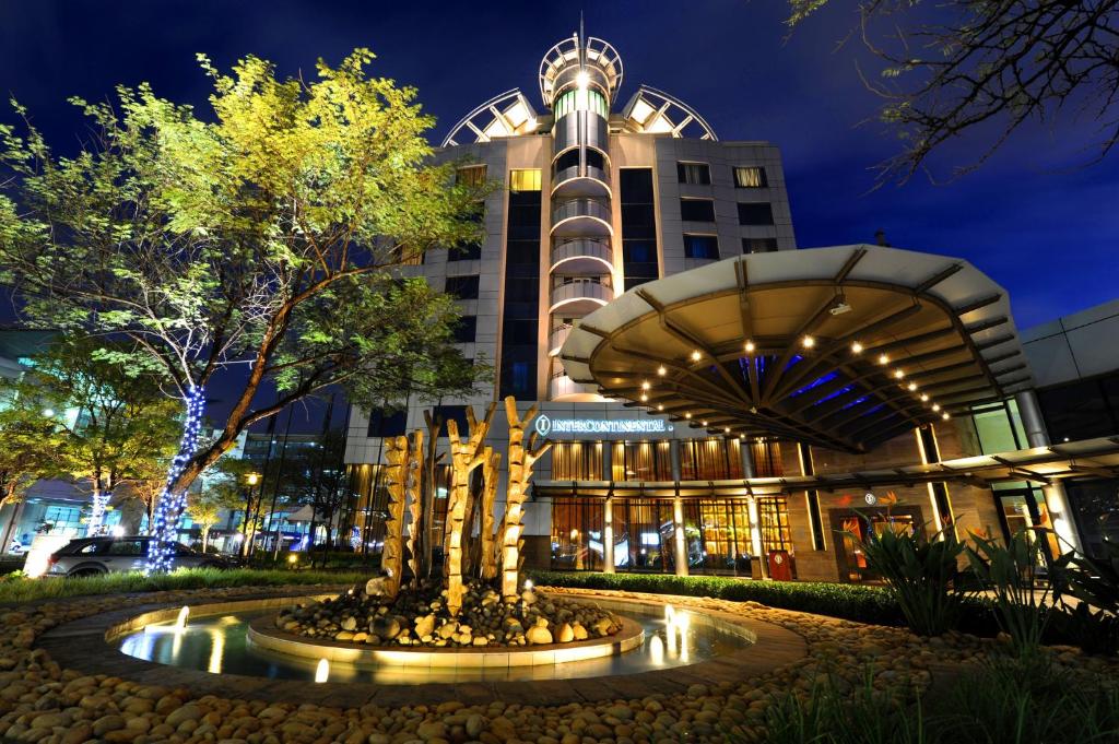 a building with a fountain in front of it at night at InterContinental Johannesburg OR Tambo Airport Hotel, an IHG Hotel in Kempton Park