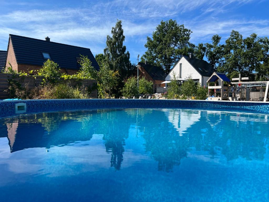 a swimming pool with blue water in front of a house at Ulinia Zacisze Dom Comfort 70m2 in Ulinia