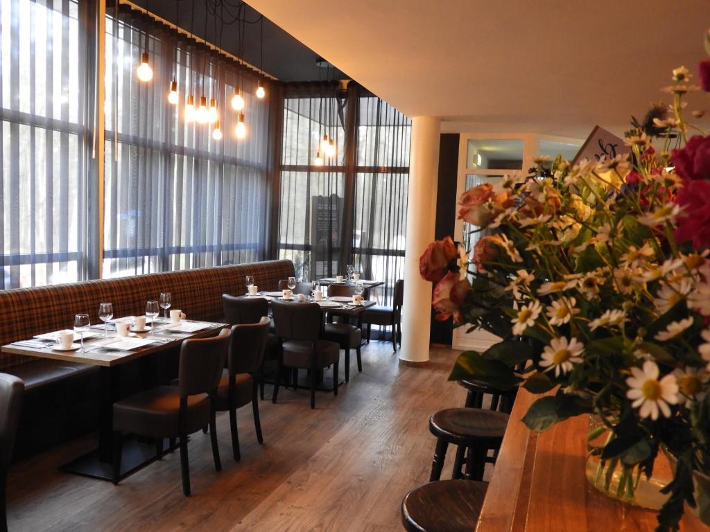 un comedor con mesas, sillas y flores en hotel de Tipmast, en Bladel