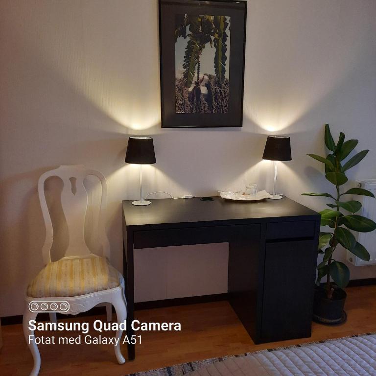 - un bureau avec deux lampes et une chaise dans la chambre dans l'établissement Naturnära dubbelrum B&B i Uppsala Ramstalund, à Uppsala