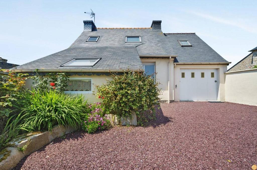 une maison avec un garage blanc et quelques plantes dans l'établissement Maison agréable 6 pers à l'Ile Grande, proche plages en PLEUMEUR-BODOU REF-268, à Pleumeur-Bodou