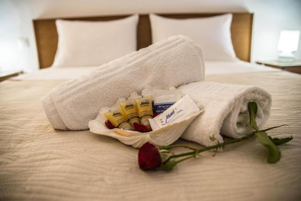 a towel on a bed with a rose on it at STAR PARADISE Studios in Neos Marmaras