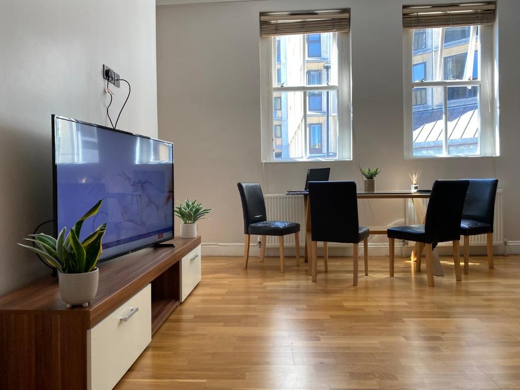 a living room with a flat screen tv and chairs at Sight Flats - SF01 - One Bedroom in London