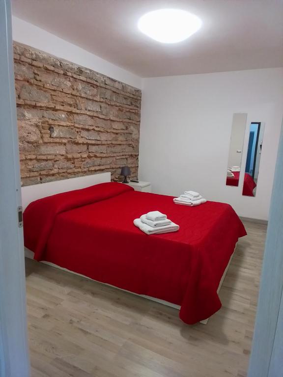 a bedroom with a red bed with a brick wall at Loft Home Sweet Home in Catania