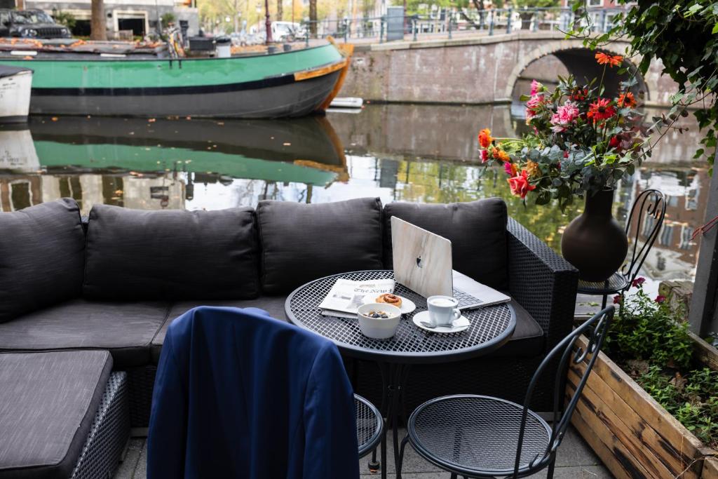 a table with a couch and a bowl of food on it at Amsterdam Canal Hotel in Amsterdam