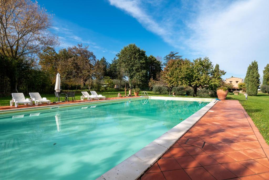 a swimming pool in a yard with chairs and trees at Villa La Tinaia Il Sole Verde in Bucine
