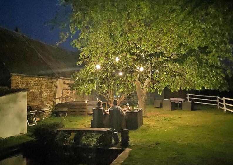 a group of people sitting at a table under a tree at Chez Aurélia - Chambres &amp; Table d&#39;hôtes in La Couture-Boussey