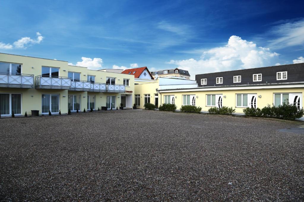 a row of white buildings on a gravel road at Hotel Fruerlund in Flensburg