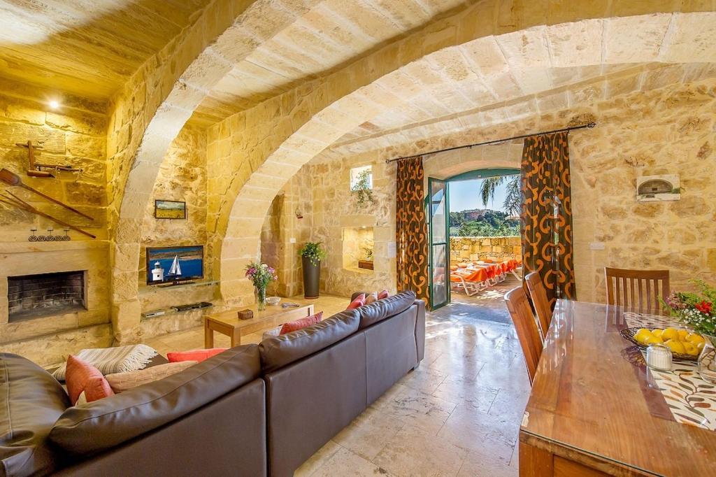 una gran sala de estar con una pared de piedra. en Razzett Tuta Holiday Home en Kerċem