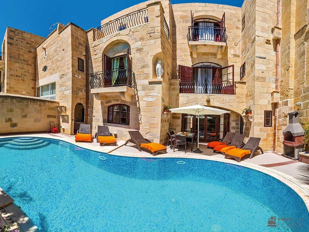 a swimming pool in front of a building at Ta' Majsi Holiday Home in Xlendi