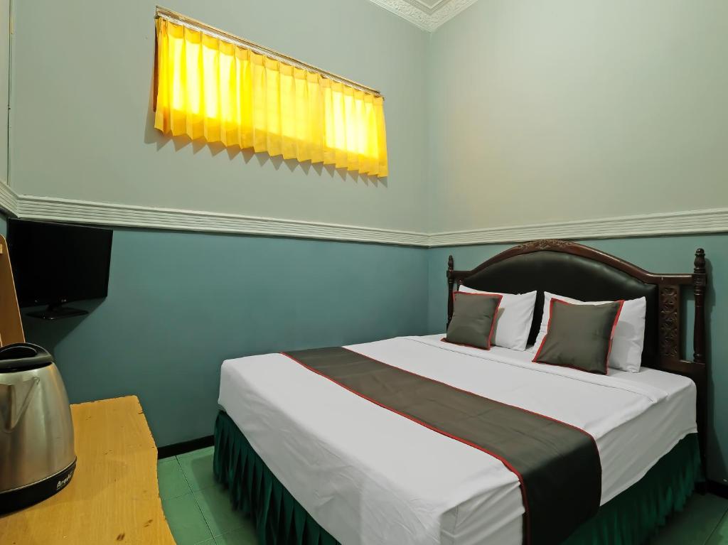 1 dormitorio con 1 cama grande y ventana en Collection O 91914 Hotel Citra Dewi 2 Int's, en Semarang